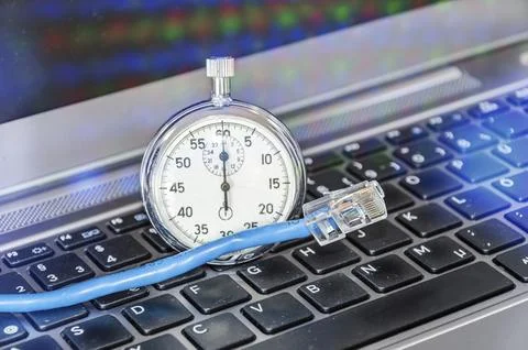 Cable and stopwatch on computer keyboard symbolizing bandwidth of internet Stock Photos