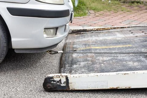 Cable attached to broken down car being pulled onto tow truck Foto stock