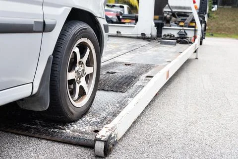 Cable attached to broken down car being pulled onto tow truck Stock Photos
