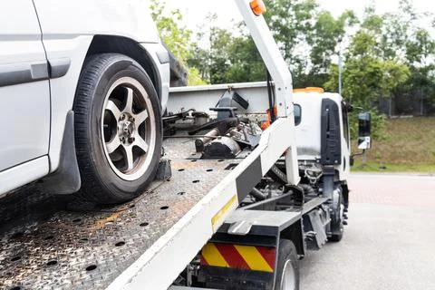 Cable attached to broken down car being pulled onto tow truck Stock Photos