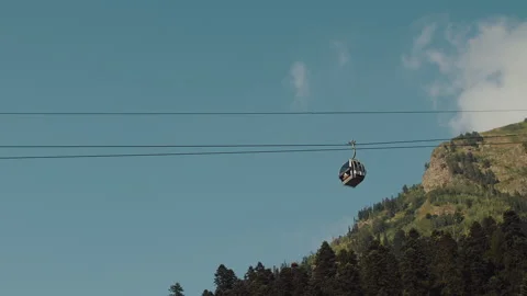 Cable car against the background of hills, coniferous trees and blue sky Stock Footage 252262850