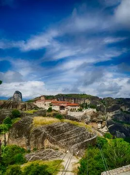 Cable car approaching monastery perched on rocky pillar amid dramatic Meteo.. Stock Photos