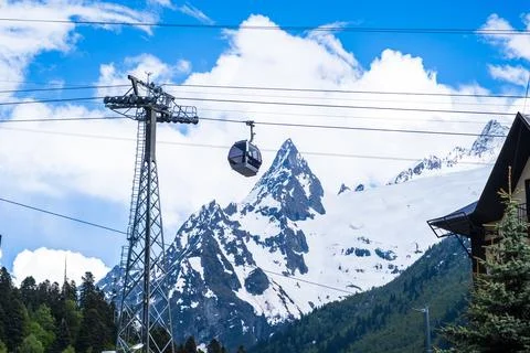 Cable car ascending through snow-covered mountains under a clear blue sky with Stock Photos
