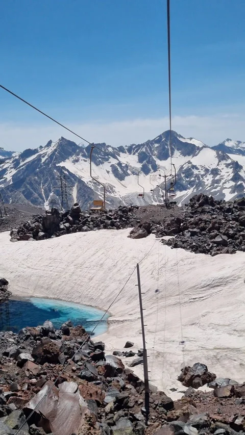 Cable car ascends a snowy mountain, revealing a turquoise lake and a Stock Footage 315067140