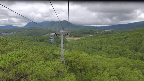 A cable car cabin floats above the treetops of pine trees in Asian mountains. Stock Footage 318570349