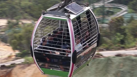 The cable car cabin rides over the hilly landscape and enters the station Stock Footage 316098907