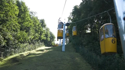 Cable car, cabins with people moving along the cable car, sunny day, green hills Stock Footage 165730096