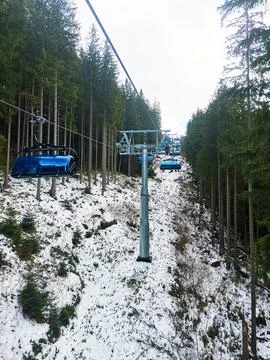 Cable car with closed cabins, moving through wooded area among fir trees Stock Photos