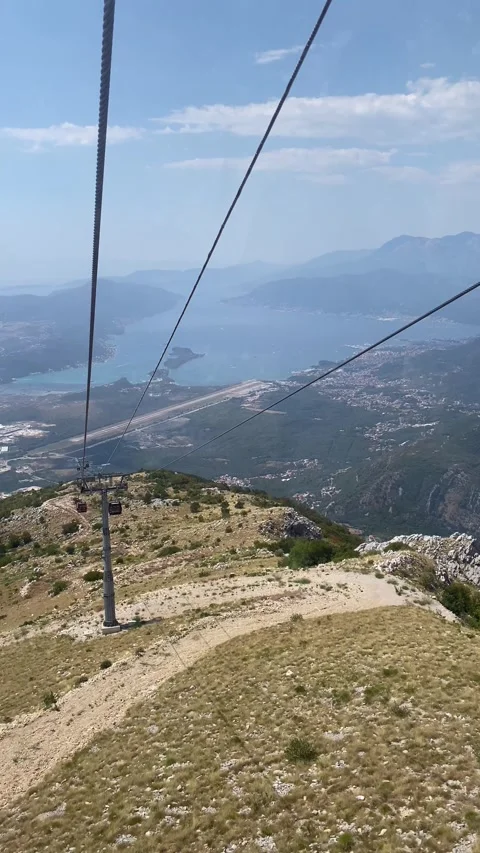 Cable car descends Lovcen mountain, over the Bay of Kotor and Tivat Airport Vídeos de archivo 343790437