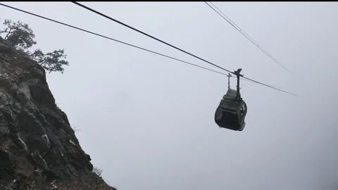 Cable car going up and down in fog on the mountains peak - misty weather sky. 4K Stock Footage 220068059