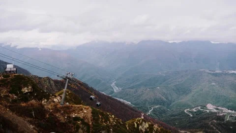 Cable car gondolas over mountain valley with misty peaks 動画素材 347734904