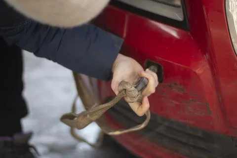 Cable for car. Guy hooks car for towing. Hand holds carabiner for screwing in Foto stock