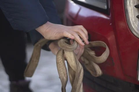 Cable for car. Guy hooks car for towing. Hand holds carabiner for screwing in Foto stock