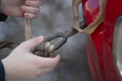 Cable for car. Guy hooks car for towing. Hand holds carabiner for screwing in Stock Photos
