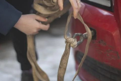 Cable for car. Guy hooks car for towing. Hand holds carabiner for screwing in Foto stock