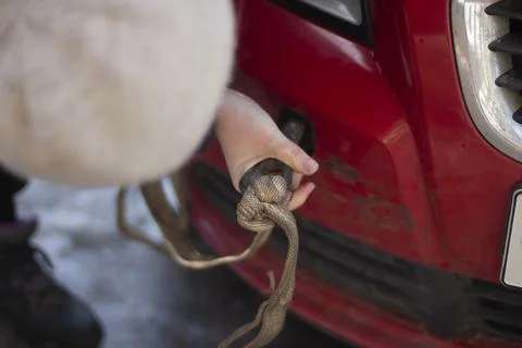 Cable for car. Guy hooks car for towing. Hand holds carabiner for screwing in Foto stock