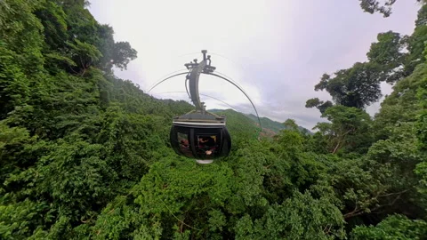 Cable Car Hovering Above Dense Forest with Visible Buildings and Far Hills Seen 库存影片 323474371