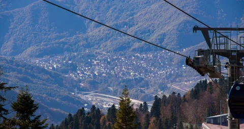 The cable car moving in  mountains. Summer nature is reflected in glass cabins Видео 130913567
