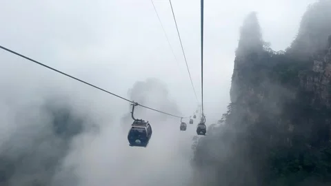 Cable car moving through thick fog over mountain peaks. Stock Footage 337649042