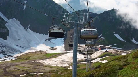 A cable car with open cabins runs over a landscape of mountain slopes Stock Footage 315066043