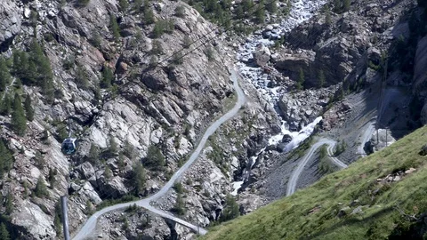 A cable car passes over a river trickling down from the Swiss Alps Stock Footage 114838870