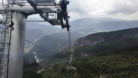 Cable Car Ride Over Green Mountain Valley with River and Clouds Stock Footage 340131524