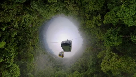 Cable Car Suspended Above Forest Ring in Dramatic Hole Planet Effect with Mounta 스톡 동영상 323478085