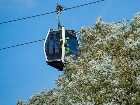 A cable car is suspended above the tree. Stock Photos