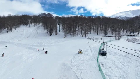 Cable car transporting tourists to the mountain peak over snowy ski trails Video stock 327584105