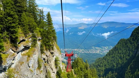 Cable car view over a mountain valley town. The red gondola structure frames Stock Footage 321538989