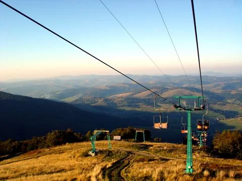 Cable car way against the backdrop of highlands and blue sky. Green cable r.. Stock Photos