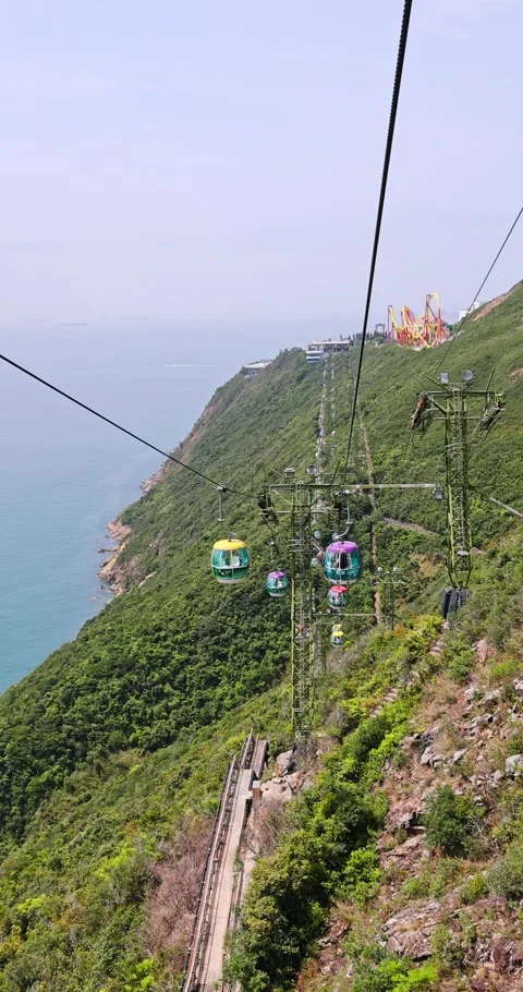 Cable Cars Transporting Passengers Over Lush Mountain by Ocean Stock Footage 326763585