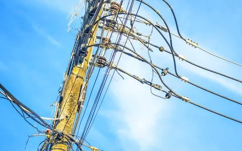 Cable clutter on a power pole in town blue sky. Stock Photos