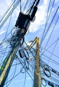 Cable clutter on a power pole in town blue sky. Stock Photos