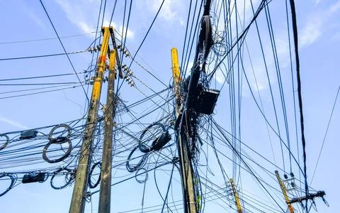 Cable clutter on a power pole in town blue sky. Stock Photos