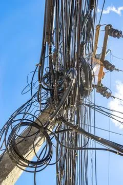 Cable clutter on a power pole in town blue sky. Stock Photos