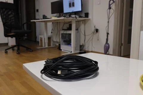 Cable is placed on a table in a room with a computer setup and other items Stock Photos