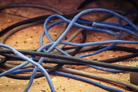 Cable power cords in a tangled mess on floor of workplace, used dirty electri Stock Photos