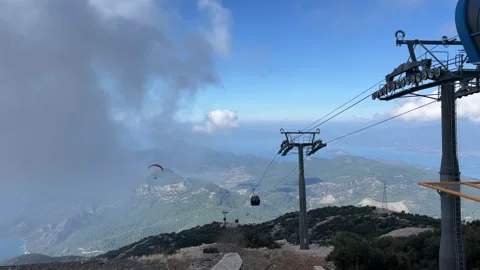 Cable railway with closed cabins passes through clouds in the mountains Stock Footage 264509983