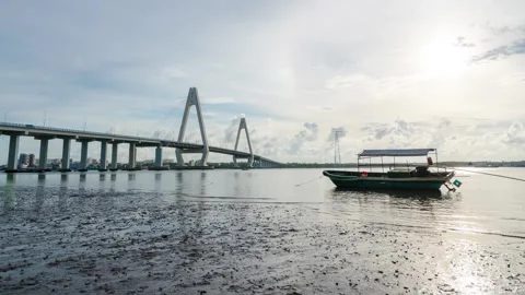 Cable-stayed bridge across the sea with fishing boat on mudflats at low tide 库存影片 348498230