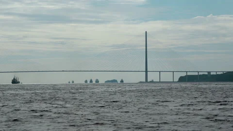 Cable-stayed bridge against sky. Vessels in silhouette on horizon. Monochrome Stock Footage 240086964