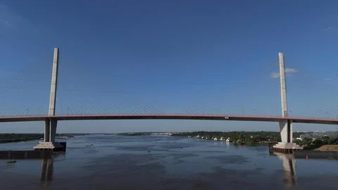 Cable-stayed bridge crosses a wide river under a clear sky Fotos de archivo