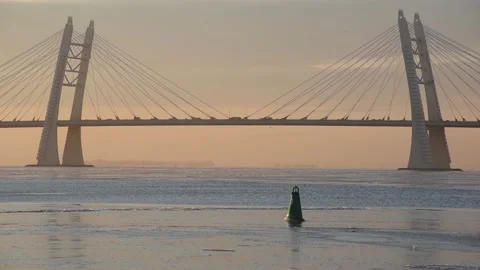 Cable-stayed bridge over water covered with ice at sunset - Russia Stock Footage 144906064