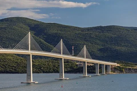 Cable-Stayed Bridge Spanning Calm Water With Mountain Landscape and Golden .. Stock Photos