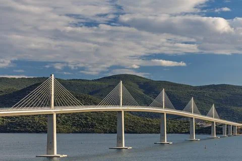 Cable-Stayed Bridge Spanning Calm Water With Mountain Landscape and Golden .. Stock Photos