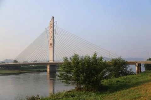 Cable stayed bridge spanning wide river with surrounding greenery and dista.. Stock Photos