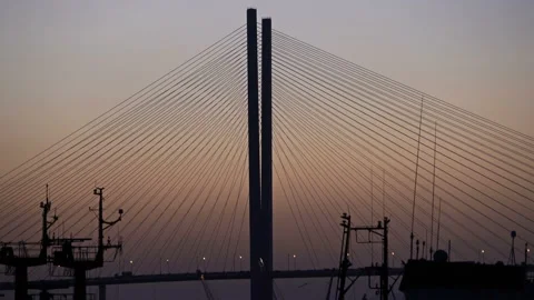 Cable stayed bridge on which many cars travel stands in silhouette at sunset Stock Footage 134887995