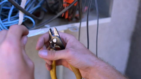Cable technician stripping and cutting wires at the DMARC point outdoors Stockbeeldmateriaal 312358371
