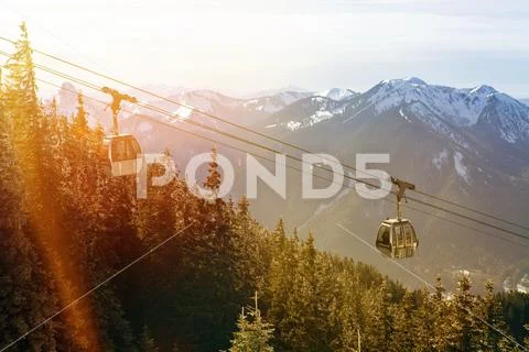 Cableway with forest and snowy mountain peaks Stock Photos
