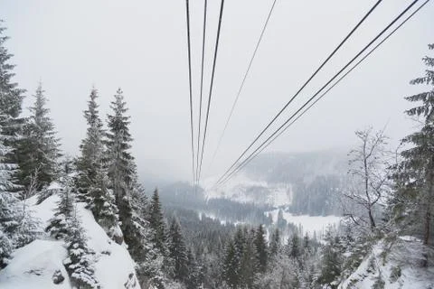 Cableway in the mountains in winter. Perspective view of the mountain woods and Stock Photos